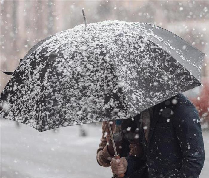 person holding umbrella during snow storm